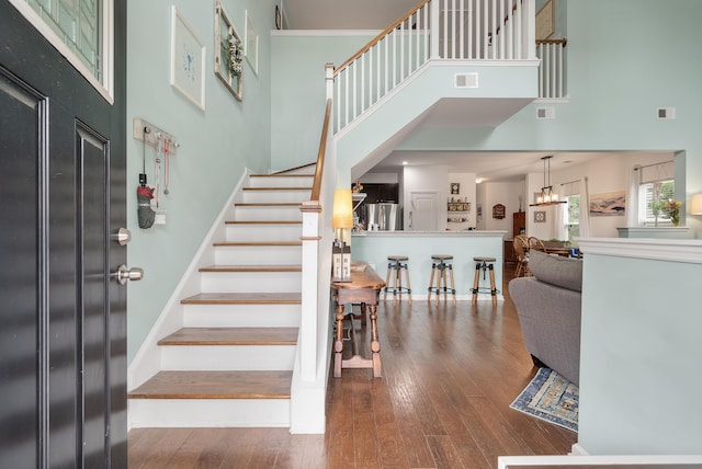 stairway with wood-type flooring and a high ceiling