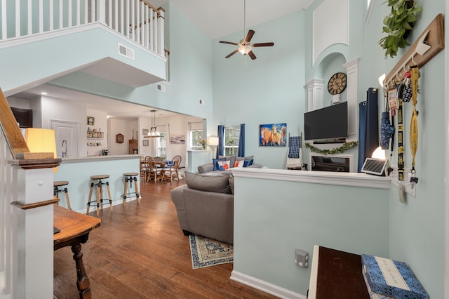 living room with ceiling fan, hardwood / wood-style flooring, and a high ceiling