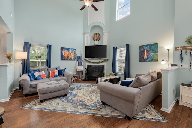 living room featuring decorative columns, hardwood / wood-style flooring, a towering ceiling, and ceiling fan