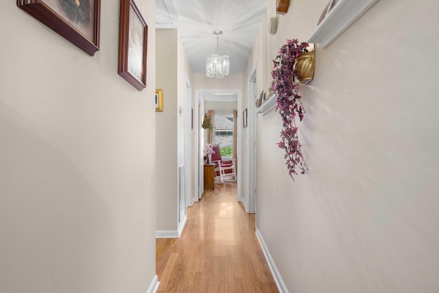 hall with a notable chandelier and light hardwood / wood-style floors