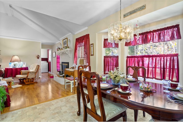 dining area with wood-type flooring, washer / clothes dryer, a fireplace, lofted ceiling with beams, and an inviting chandelier