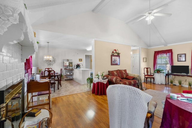 living room with vaulted ceiling with beams, light hardwood / wood-style flooring, sink, and ceiling fan with notable chandelier