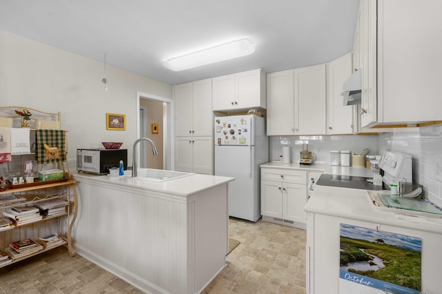 kitchen featuring kitchen peninsula, sink, white cabinetry, white appliances, and tasteful backsplash