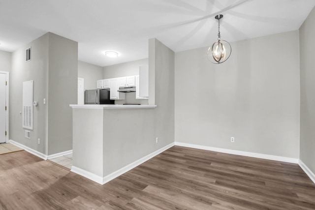 1600 Long Grove Dr Unit 423, Mount Pleasant, SC 29464 - kitchen with freestanding refrigerator, under cabinet range hood, wood finished floors, a chandelier, and white cabinets