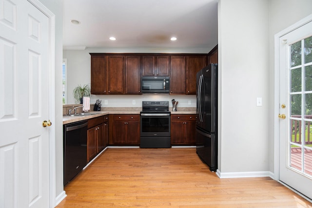 kitchen featuring black appliances, dark brown cabinets, sink, and light hardwood / wood-style floors