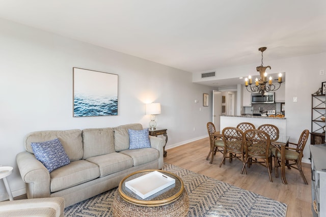 living room with an inviting chandelier and light hardwood / wood-style flooring