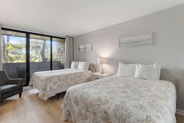 bedroom with access to outside, floor to ceiling windows, and hardwood / wood-style floors