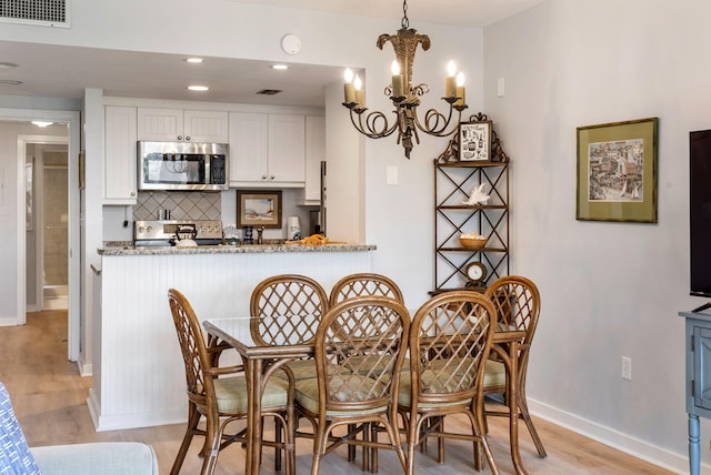 dining space featuring an inviting chandelier and light wood-type flooring