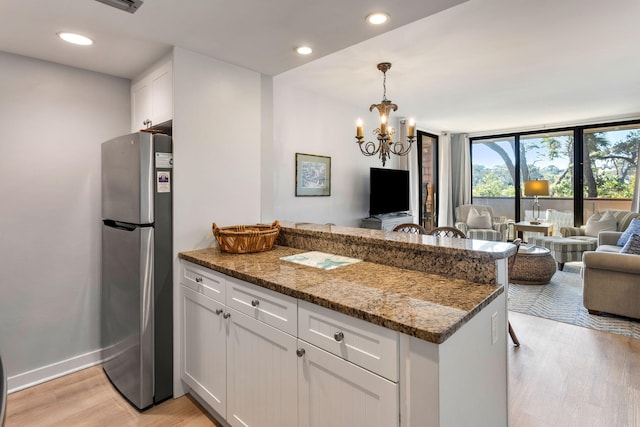 kitchen featuring stainless steel fridge, stone countertops, and white cabinetry