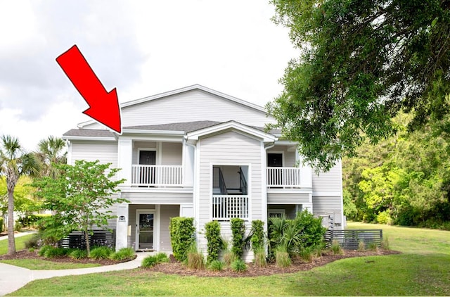 view of front of house with a balcony and a front lawn
