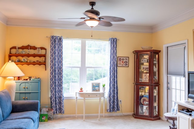 living area featuring a healthy amount of sunlight, crown molding, carpet, and a ceiling fan