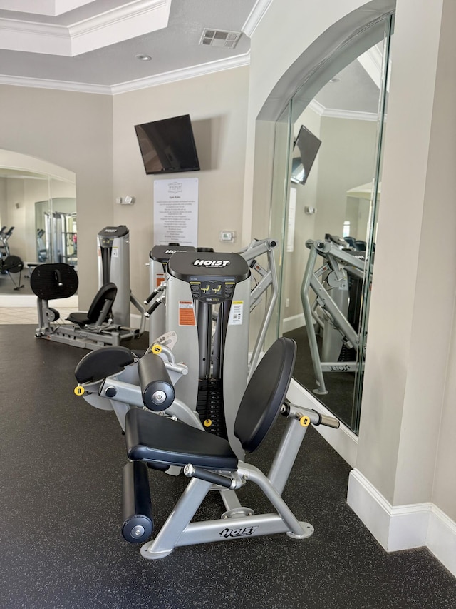exercise room with visible vents, ornamental molding, baseboards, and arched walkways