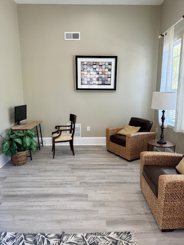 sitting room with baseboards, visible vents, and light wood-style flooring