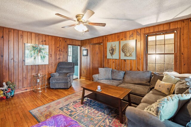 living room featuring ceiling fan, plenty of natural light, hardwood / wood-style floors, and a textured ceiling