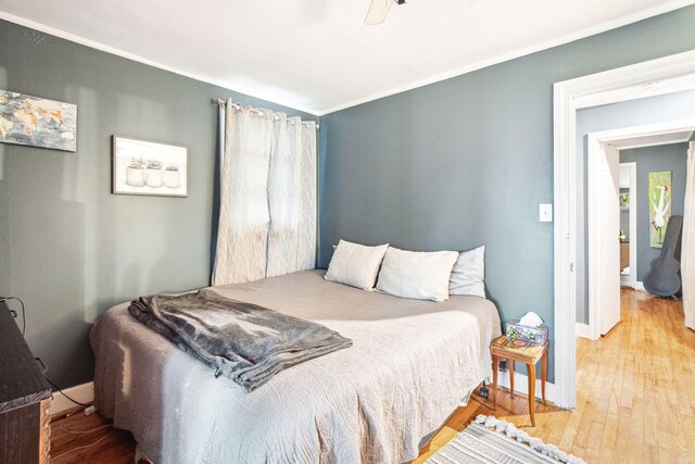 bedroom with wood-type flooring, crown molding, and ceiling fan