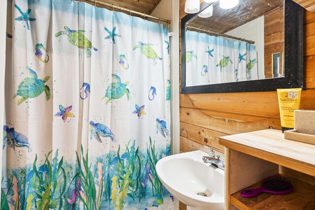 bathroom featuring wood walls, sink, and a shower with shower curtain