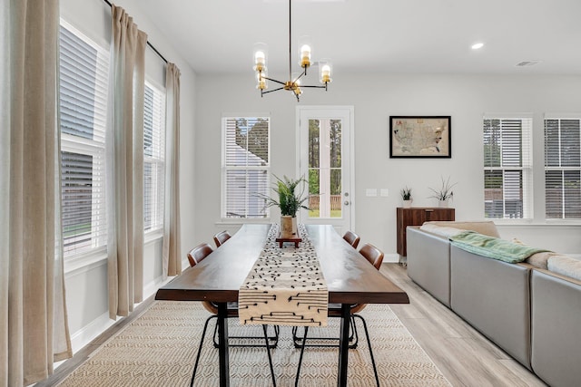 dining area featuring light wood-style floors, plenty of natural light, and a chandelier