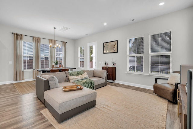 living room featuring visible vents, baseboards, an inviting chandelier, recessed lighting, and light wood-style flooring