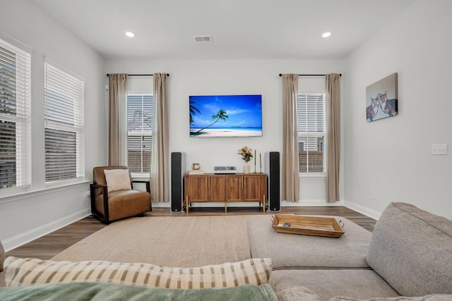 living room with baseboards, visible vents, wood finished floors, and a wealth of natural light