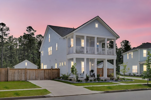 greek revival house with covered porch, fence, a balcony, and a front yard