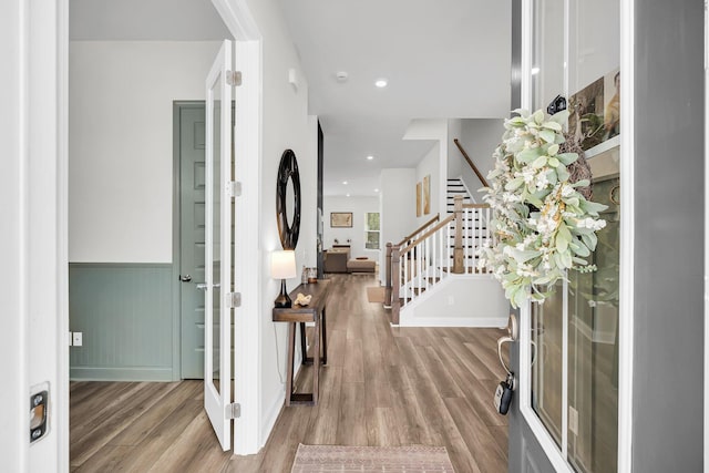 entrance foyer featuring wainscoting, stairs, and wood finished floors