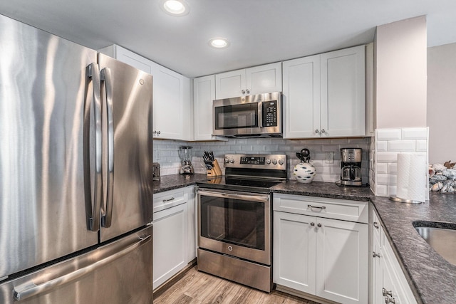 9000 Palmetto Dr Unit 202-C, Isle Of Palms, SC 29451 - kitchen featuring tasteful backsplash, light wood-type flooring, white cabinets, and stainless steel appliances