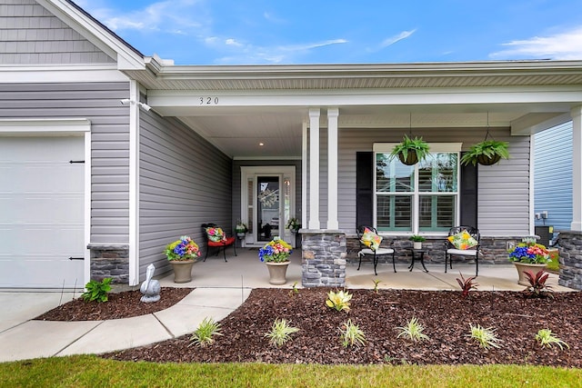 view of exterior entry featuring a garage and covered porch