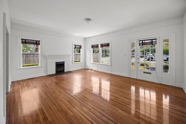 9 Wesley Dr, Charleston, SC 29407 - unfurnished living room with healthy amount of natural light, wood finished floors, a brick fireplace, and baseboards
