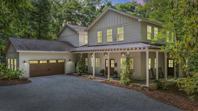 view of front of property featuring board and batten siding, a porch, a garage, and driveway
