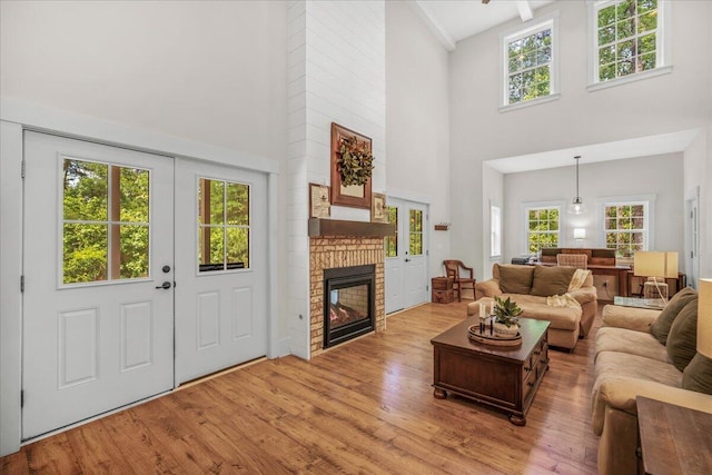 living room with a towering ceiling, wood finished floors, a fireplace, and healthy amount of natural light