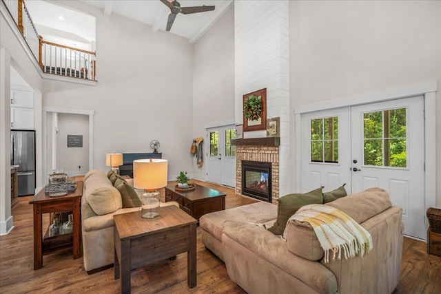 living room featuring a high ceiling, a fireplace, wood finished floors, and ceiling fan