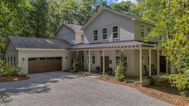 view of front of home featuring board and batten siding, an attached garage, driveway, a porch, and metal roof
