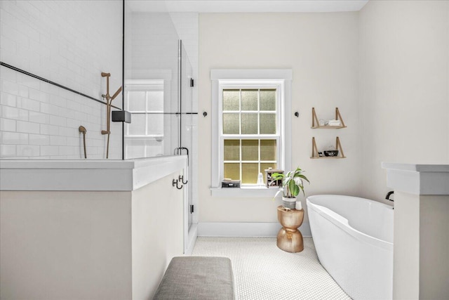 bathroom with a shower with door, a freestanding bath, and baseboards