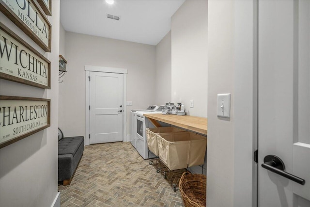 washroom featuring washer and clothes dryer and brick flooring