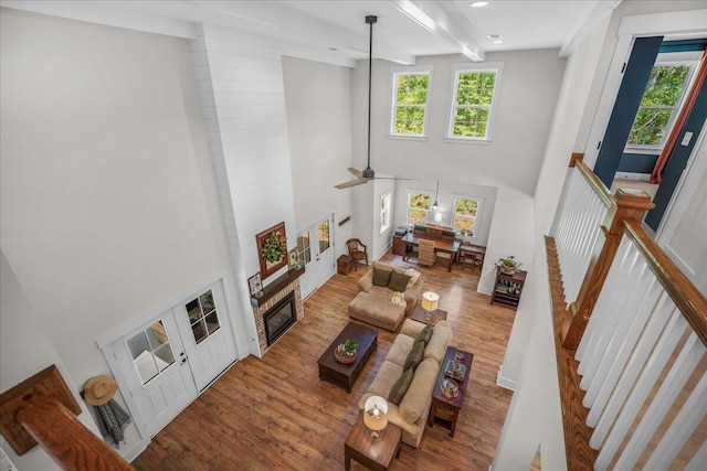 living room featuring a high ceiling, wood finished floors, plenty of natural light, beam ceiling, and stairs