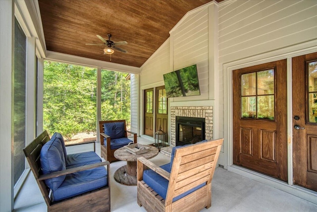 sunroom / solarium with vaulted ceiling, ceiling fan, and a brick fireplace