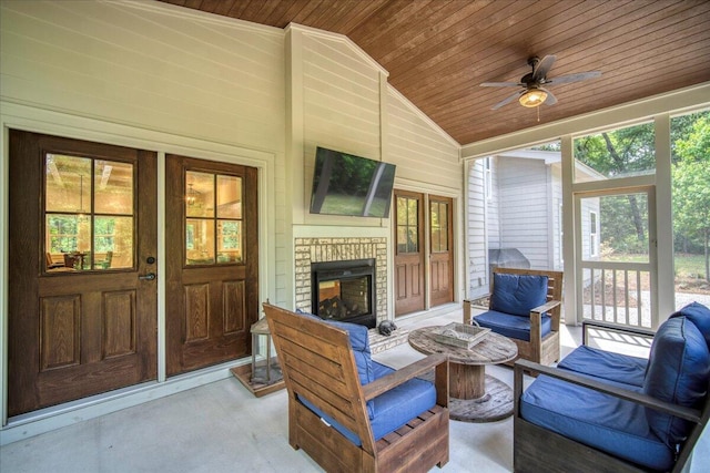 sunroom with lofted ceiling, healthy amount of natural light, ceiling fan, and an outdoor living space with a fireplace