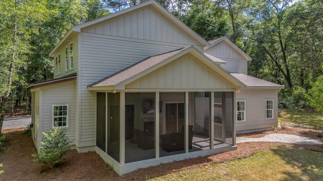 back of house featuring roof with shingles, a sunroom, and board and batten siding