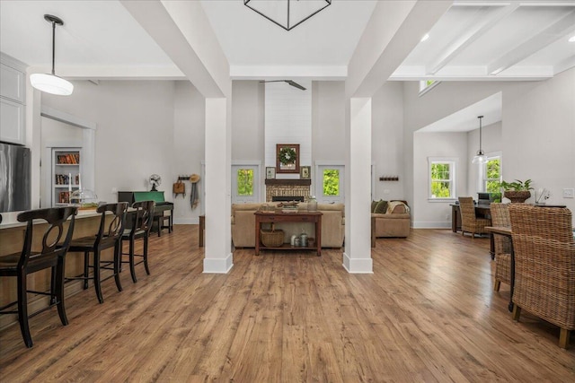 interior space with refrigerator, beamed ceiling, a towering ceiling, light wood finished floors, and baseboards