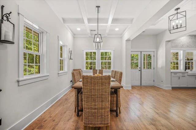 dining area with coffered ceiling, baseboards, a chandelier, light wood-style flooring, and healthy amount of natural light