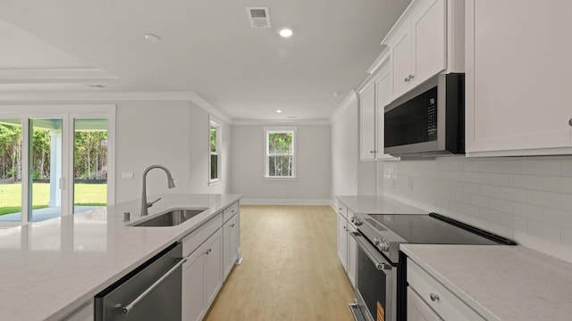 205 Bilge Rd, Ridgeville, SC 29472 - kitchen with appliances with stainless steel finishes, white cabinets, decorative backsplash, crown molding, and light wood-style floors
