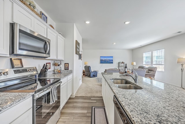 kitchen featuring recessed lighting, a sink, white cabinets, appliances with stainless steel finishes, and open floor plan