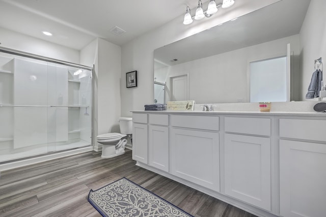 bathroom with vanity, wood finished floors, visible vents, a shower stall, and toilet