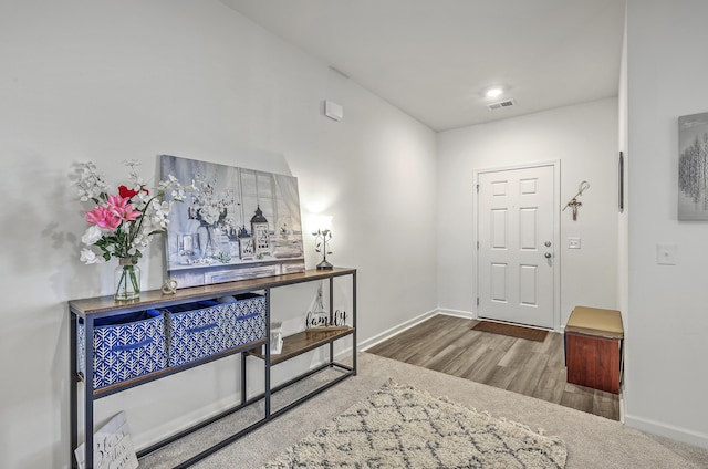 foyer featuring visible vents, baseboards, and wood finished floors