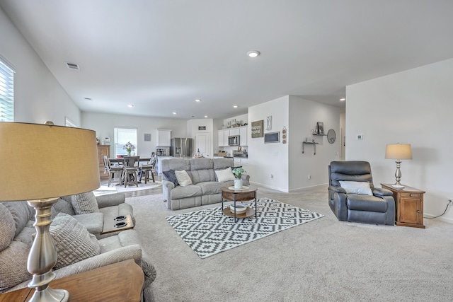 living room with recessed lighting, visible vents, light colored carpet, and baseboards