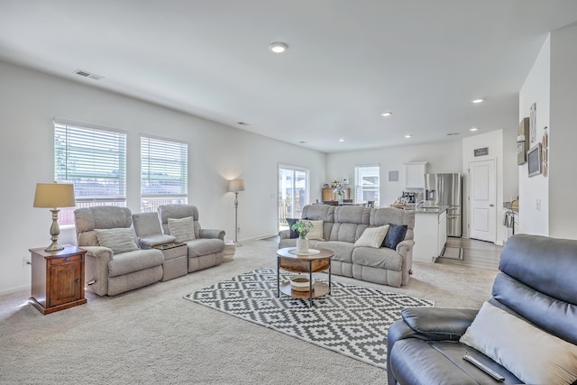 living room with light carpet, visible vents, recessed lighting, and baseboards