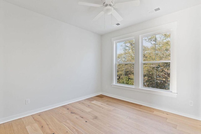 empty room featuring visible vents, light wood finished floors, and a wealth of natural light