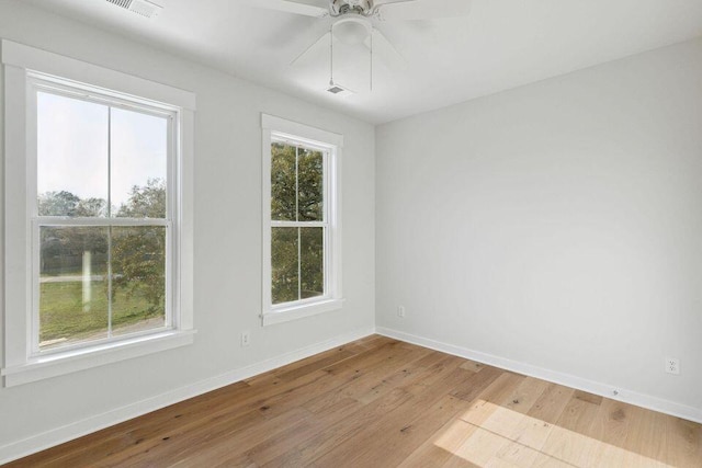 unfurnished room featuring a ceiling fan, visible vents, baseboards, and wood finished floors