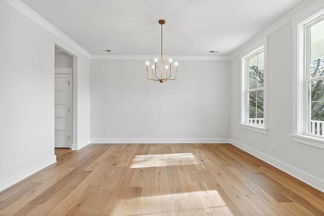 unfurnished room featuring an inviting chandelier, light wood-style flooring, baseboards, and crown molding