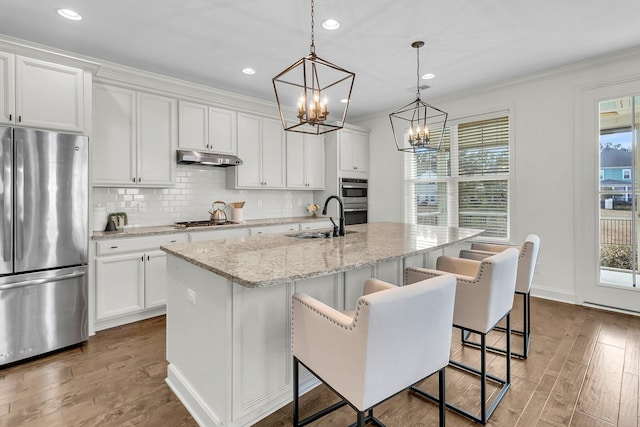 kitchen featuring white cabinets, sink, an island with sink, and appliances with stainless steel finishes